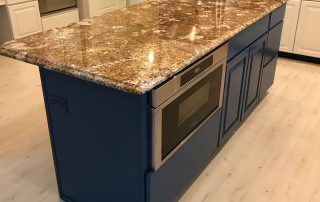 A marble kitchen table top with navy blue cabinets