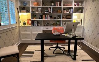 A room with laptop on a table and a shelf in the background